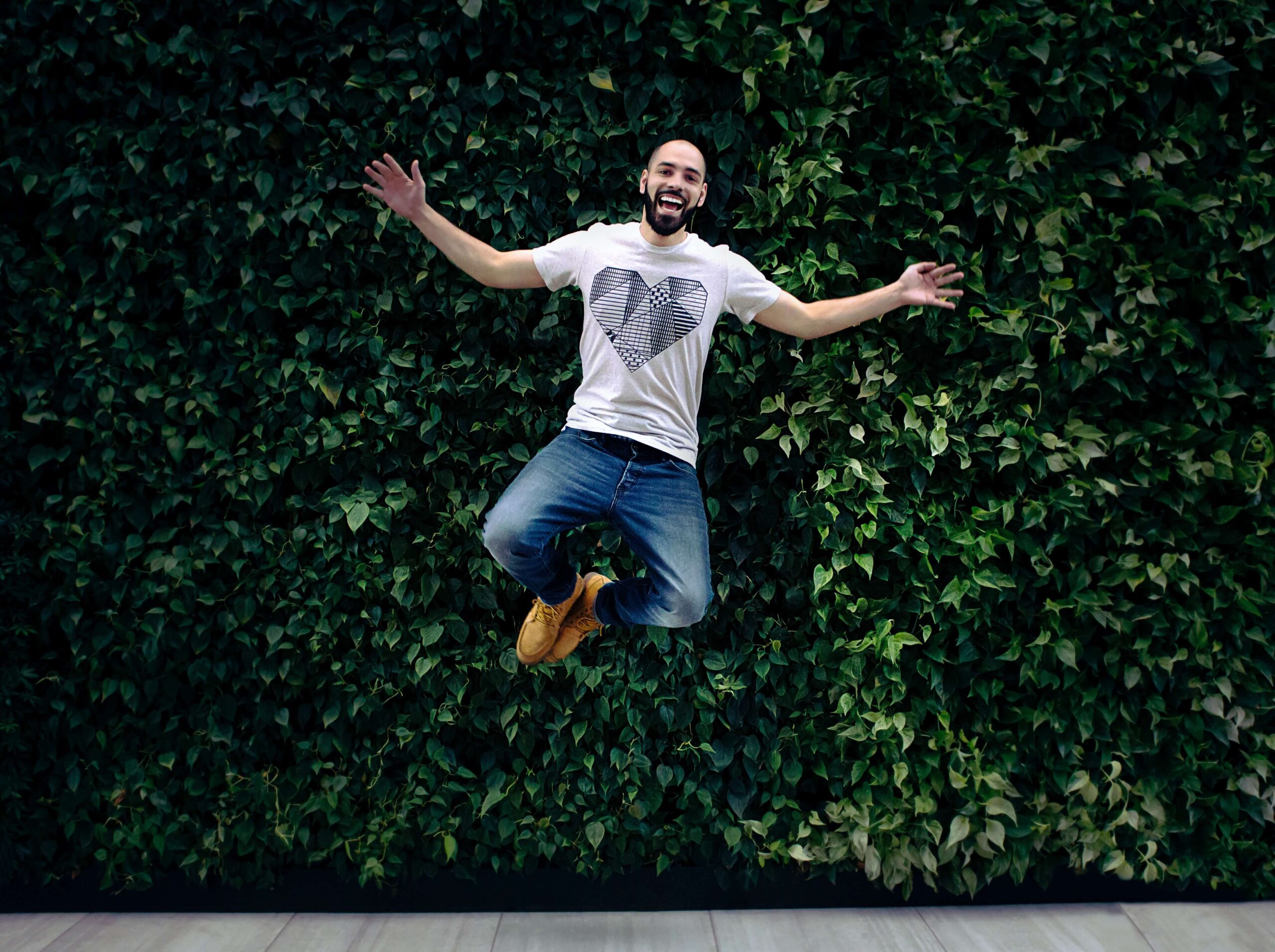 Szczęśliwy mężczyzna skacze ba tle zielonej ściany
