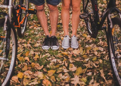 Kobieta i mężczyzna stoją w lesie ze swoimi rowerami. Mają na sobie trampki.