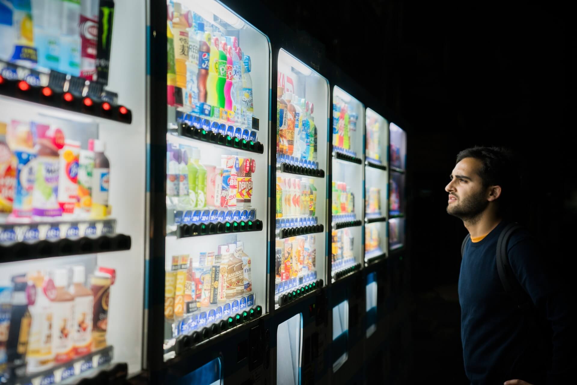 Mężczyzna stoi na przeciwko automatów z jedzeniem
